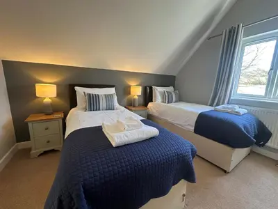 a bedroom with two beds and a window at Trewhiddle Retreat V14 by Together Travel - Luxury 4-Bedroom Villa in St Austell