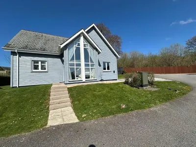 a white house with large windows on a street at Trewhiddle Retreat V14 by Together Travel - Luxury 4-Bedroom Villa in St Austell