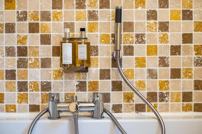 a bath tub with a hose attached to a tile wall at Trewhiddle Retreat V16 by Together Travel - Luxury 4-Bedroom Villa in St Austell