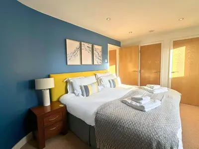 a bedroom with a large bed and a blue wall at Trewhiddle Retreat V16 by Together Travel - Luxury 4-Bedroom Villa in St Austell