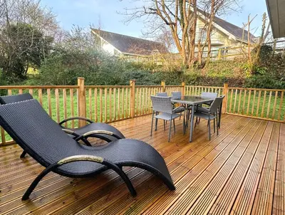 a deck with chairs and a table and a table and chairs at Trewhiddle Retreat V16 by Together Travel - Luxury 4-Bedroom Villa in St Austell