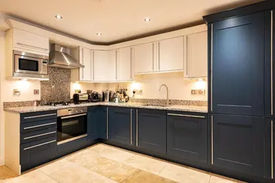 a kitchen with white cabinets and blue appliances at Trewhiddle Retreat V16 by Together Travel - Luxury 4-Bedroom Villa in St Austell
