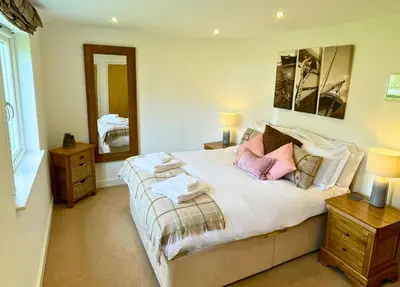 a bedroom with a bed with two lamps and a mirror at Trewhiddle Retreat V12 by Together Travel - Luxury 4-Bedroom Villa in St Austell