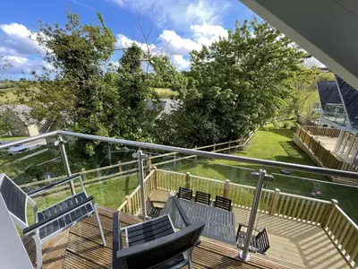 a deck with chairs and a view of a yard at Trewhiddle Retreat V12 by Together Travel - Luxury 4-Bedroom Villa in St Austell