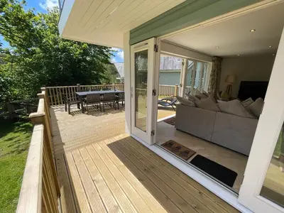 a deck with a sliding glass door with a couch at Trewhiddle Retreat V12 by Together Travel - Luxury 4-Bedroom Villa in St Austell
