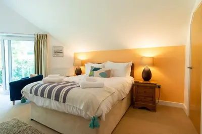 a bedroom with a large bed and a window at Trewhiddle Retreat V11 by Together Travel - Luxury 4-Bedroom Villa in St Austell