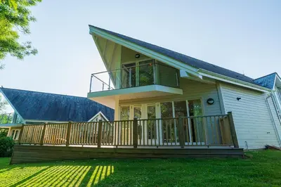 a house with a large deck on a lawn at Trewhiddle Retreat V11 by Together Travel - Luxury 4-Bedroom Villa in St Austell