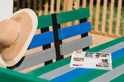 a straw hat sitting on a bench with a newspaper at Trewhiddle Retreat V10 by Together Travel - Luxury 4-Bedroom Villa in St Austell