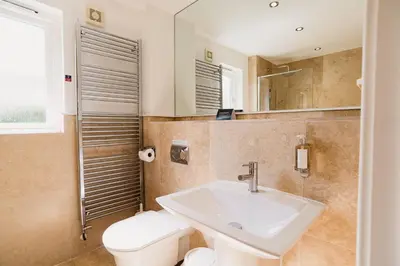 a bathroom with a sink and a toilet and a mirror at Trewhiddle Retreat V10 by Together Travel - Luxury 4-Bedroom Villa in St Austell