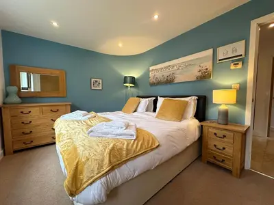 a bedroom with a large bed and blue walls at Trewhiddle Retreat V10 by Together Travel - Luxury 4-Bedroom Villa in St Austell