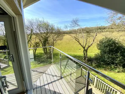 a balcony with a view of a field from a house at Trewhiddle Retreat V19 by Together Travel - Luxury 4-Bedroom Villa in St Austell