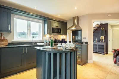 a kitchen with blue cabinets and a large island in the middle at Trewhiddle Retreat V5 by Together Travel - Luxury 4-Bedroom Villa in St Austell
