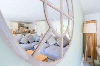 a living room with a couch and a large mirror at Trewhiddle 41 by Together Travel - Stylish Coastal Countryside Retreat in St Austell