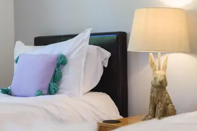 a bed with pillows and a stuffed rabbit on a table at Trewhiddle 41 by Together Travel - Stylish Coastal Countryside Retreat in St Austell