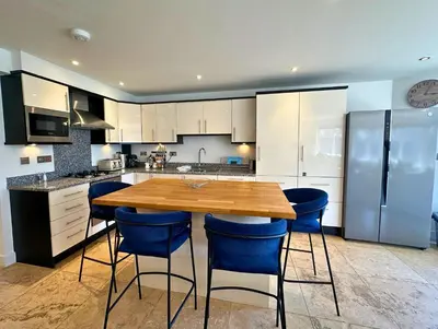 a kitchen with a wooden table and blue chairs at Trewhiddle Retreat V30 by Together Travel - Luxury 4-Bedroom Villa in St Austell