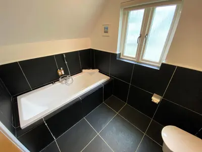a bathroom with a bath tub and a toilet at Trewhiddle Retreat V30 by Together Travel - Luxury 4-Bedroom Villa in St Austell