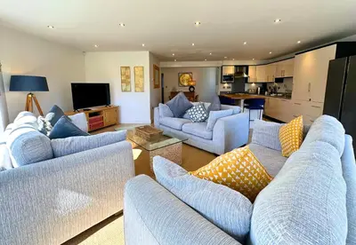 a living room with blue couches and a kitchen at Trewhiddle Retreat V30 by Together Travel - Luxury 4-Bedroom Villa in St Austell