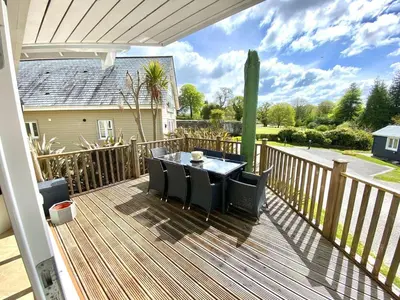 a patio with a table and chairs on a deck at Trewhiddle Retreat V30 by Together Travel - Luxury 4-Bedroom Villa in St Austell