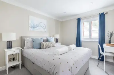 a bedroom with a bed with blue curtains and a desk at Hideaway - Exclusive marina development, town centre, with parking in Falmouth