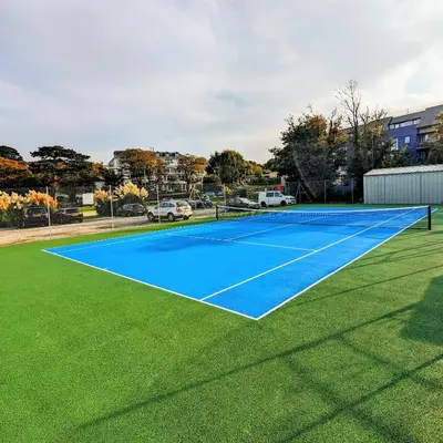 a blue tennis court with green grass at Hideaway - Exclusive marina development, town centre, with parking in Falmouth