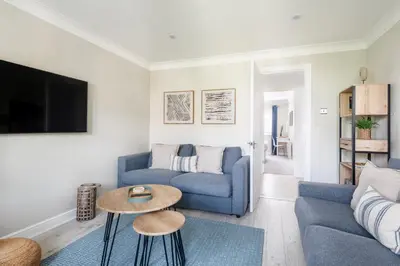 a living room with a blue couch and a table at Hideaway - Exclusive marina development, town centre, with parking in Falmouth