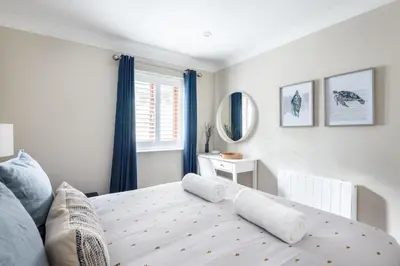 a bedroom with a bed with blue curtains and a window at Hideaway - Exclusive marina development, town centre, with parking in Falmouth