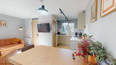 a living room with a table and a kitchen at 19 Strawberry Hill, Tolroy Manor in Hayle