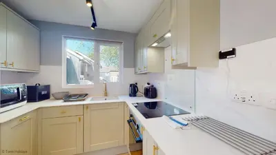 a kitchen with white cabinets and a sink and a window at 19 Strawberry Hill, Tolroy Manor in Hayle