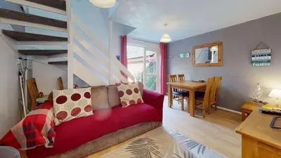 a living room with a red couch and a table at 24 Strawberry Hill, Tolroy Manor in Hayle