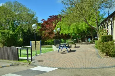 a park with a picnic table on a brick sidewalk at 24 Strawberry Hill, Tolroy Manor in Hayle