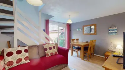 a living room with a red couch and a table at 24 Strawberry Hill, Tolroy Manor in Hayle