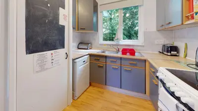 a small kitchen with blue cabinets and a sink at 24 Strawberry Hill, Tolroy Manor in Hayle