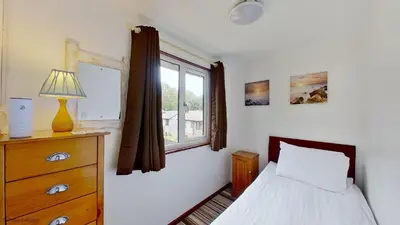 a bedroom with a bed and a window and a dresser at 36 Strawberry Hill, Tolroy Manor in Hayle