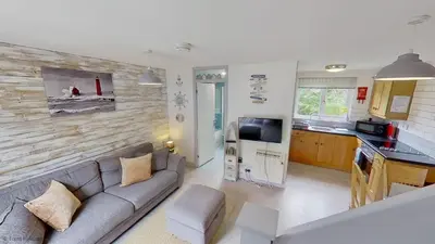 a living room with a couch and a kitchen at 36 Strawberry Hill, Tolroy Manor in Hayle