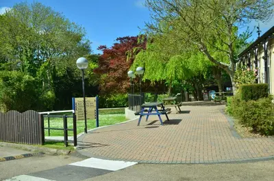 a park with a picnic table on a brick sidewalk at 15 Trevithick Court, Tolroy Manor in Hayle