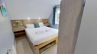 a small bedroom with a bed with white sheets at 23 Trevithick Court, Tolroy Manor in Hayle