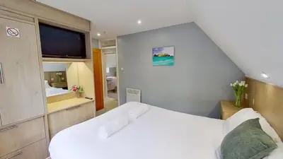 a small bedroom with a white bed and a tv at 23 Trevithick Court, Tolroy Manor in Hayle