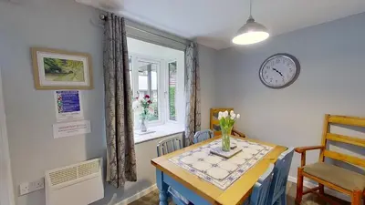 a dining room with a table and a clock on the wall at 23 Trevithick Court, Tolroy Manor in Hayle