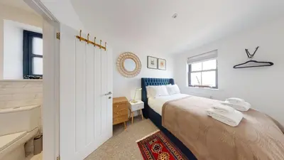 a white bedroom with a bed and a desk and a window at 05 Queensway Gardens, Hayle in Hayle