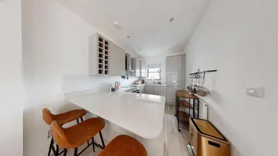 a white kitchen with a counter and chairs in it at 05 Queensway Gardens, Hayle in Hayle