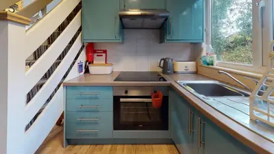 a small kitchen with blue cabinets and a sink at 34 Trevithick Court, Tolroy Manor in Hayle