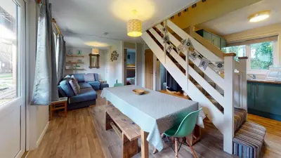 a living room with a table and a staircase at 34 Trevithick Court, Tolroy Manor in Hayle