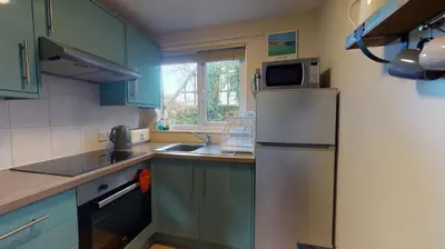 a kitchen with blue cabinets and a refrigerator with a microwave at 34 Trevithick Court, Tolroy Manor in Hayle