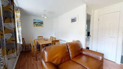 a living room with a leather couch and a table at 37 Trevithick Court, Tolroy Manor in Hayle