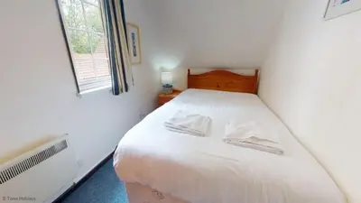 a bedroom with a white bed with two pillows on it at 15 Tudor Court, Tolroy Manor in Hayle