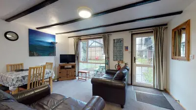 a living room with a couch and a table and chairs at 01 Tudor Court, Tolroy Manor in Hayle
