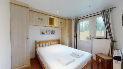 a bedroom with a bed with white sheets and a window at 01 Tudor Court, Tolroy Manor in Hayle