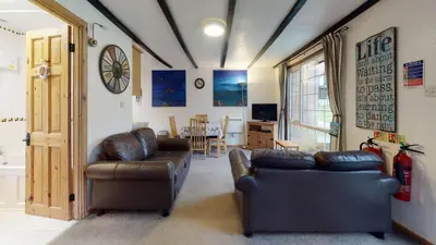 a living room with two leather couches and a television at 01 Tudor Court, Tolroy Manor in Hayle
