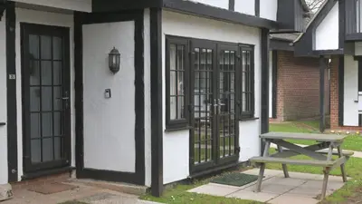 a picnic table next to a white building with black doors at 25 Tudor Court, Tolroy Manor in Hayle