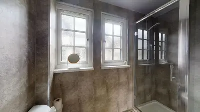 a bathroom with a shower and a toilet and windows at 25 Tudor Court, Tolroy Manor in Hayle